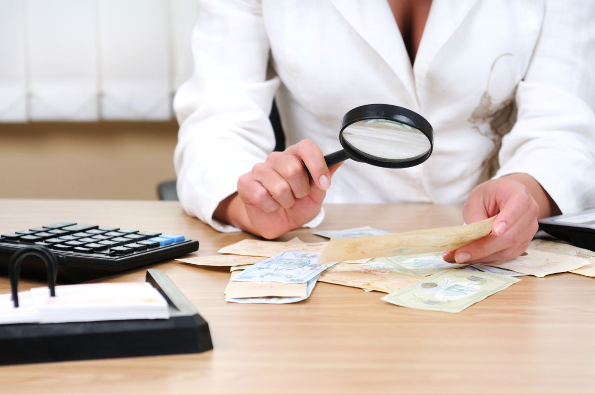 Professional in a white coat checking a document with a magnifying glass