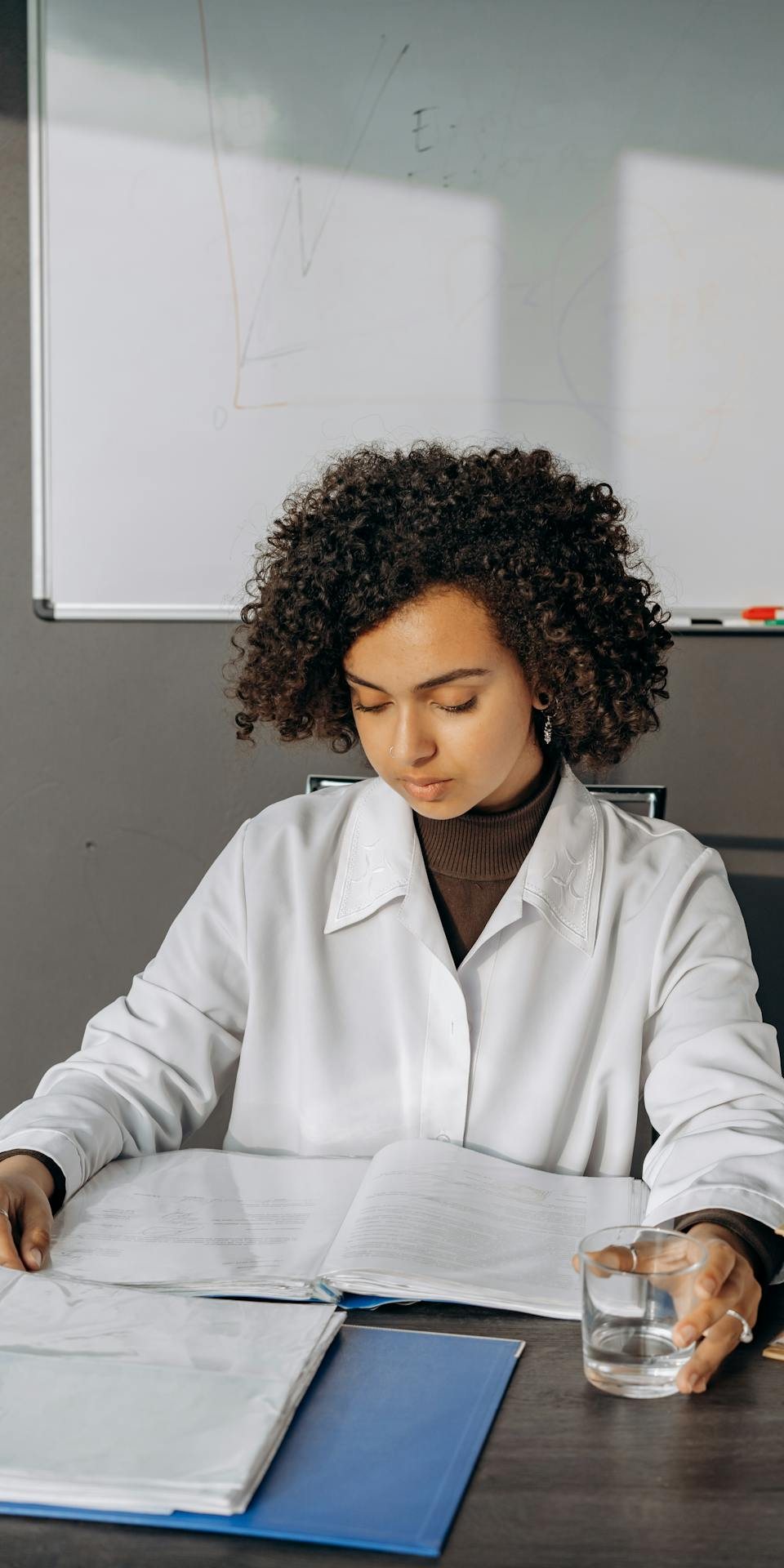 Health professional in a white coat reviewing documents at her desk