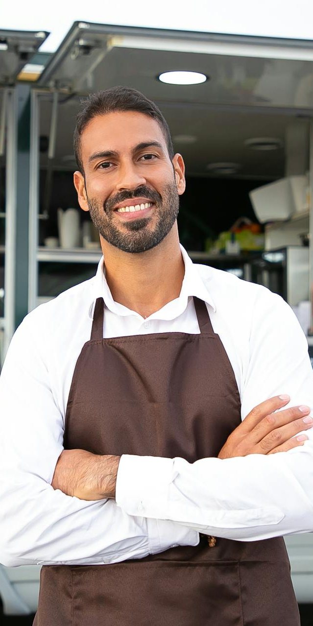 Smiling food truck owner in an apron with his arms crossed